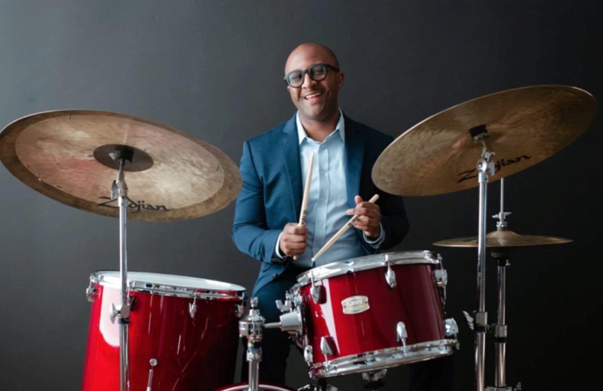 Quincy Davis sitting at a red Yamaha drum set with Zildjian cymbals